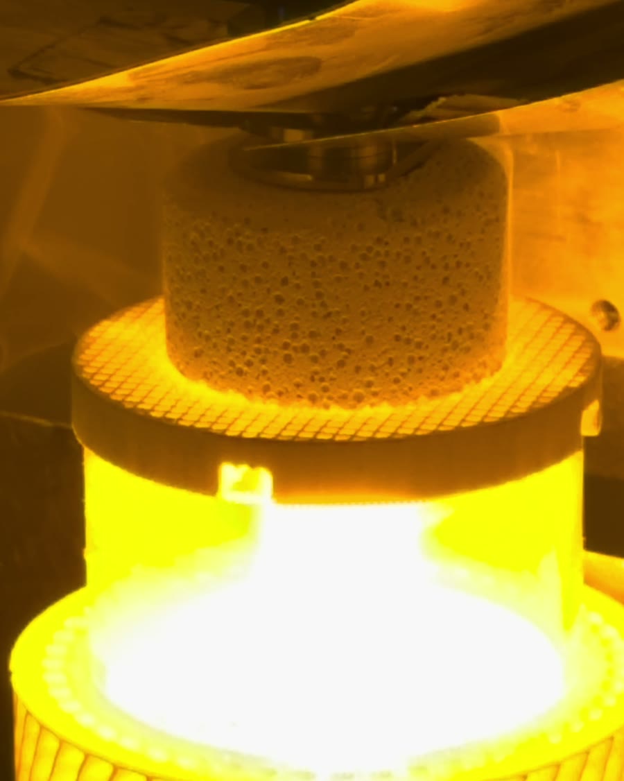 Hyperboloid burner crown glowing molten under a ceramic puck