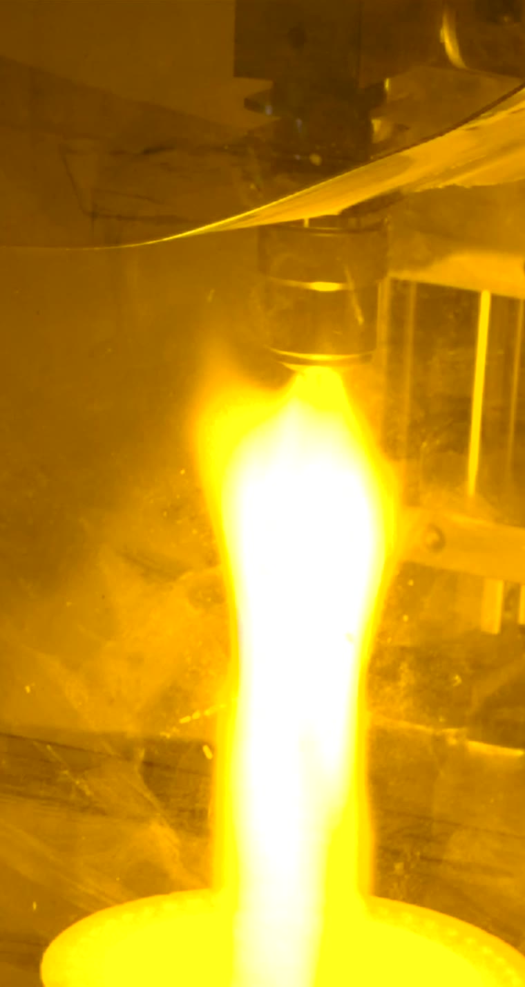 Golden flame jet rising from a glowing cup toward a nozzle